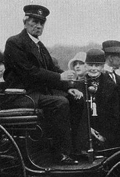 操舵柄を握るのが自動車発明者カール・ベンツ、隣が性能実証長距離走行を実行した妻ベルタ。